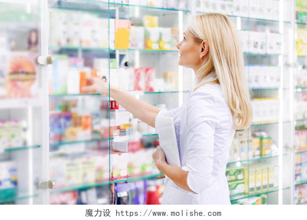 抱着数字平板和检查药物在药店的药剂师的侧视图
